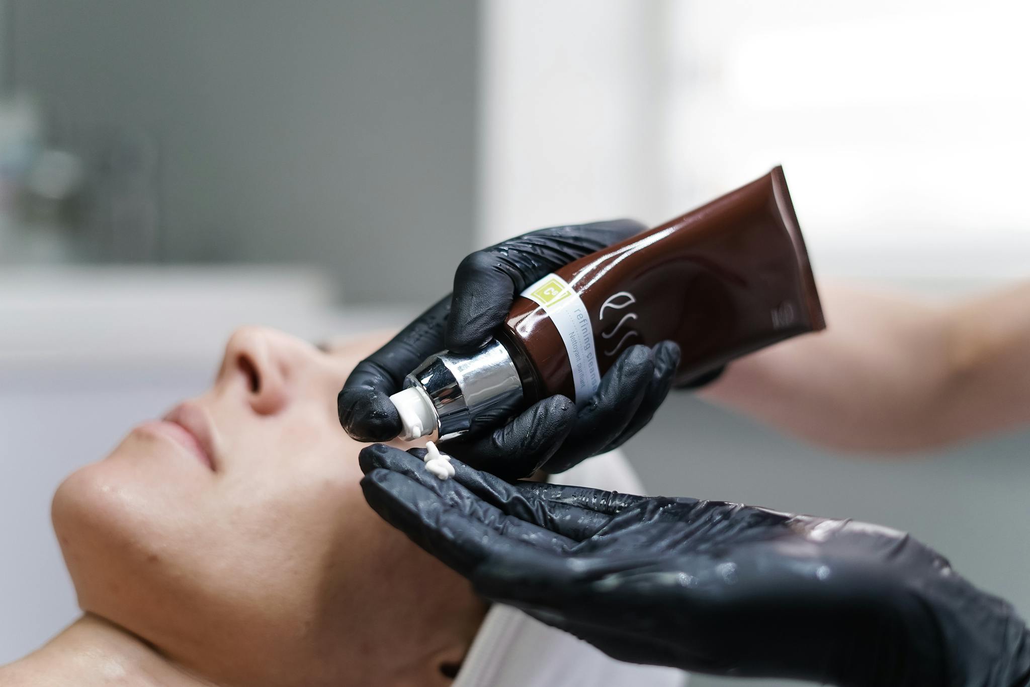 Close-up of a skincare professional applying cream with gloves during a facial treatment in a clinic.